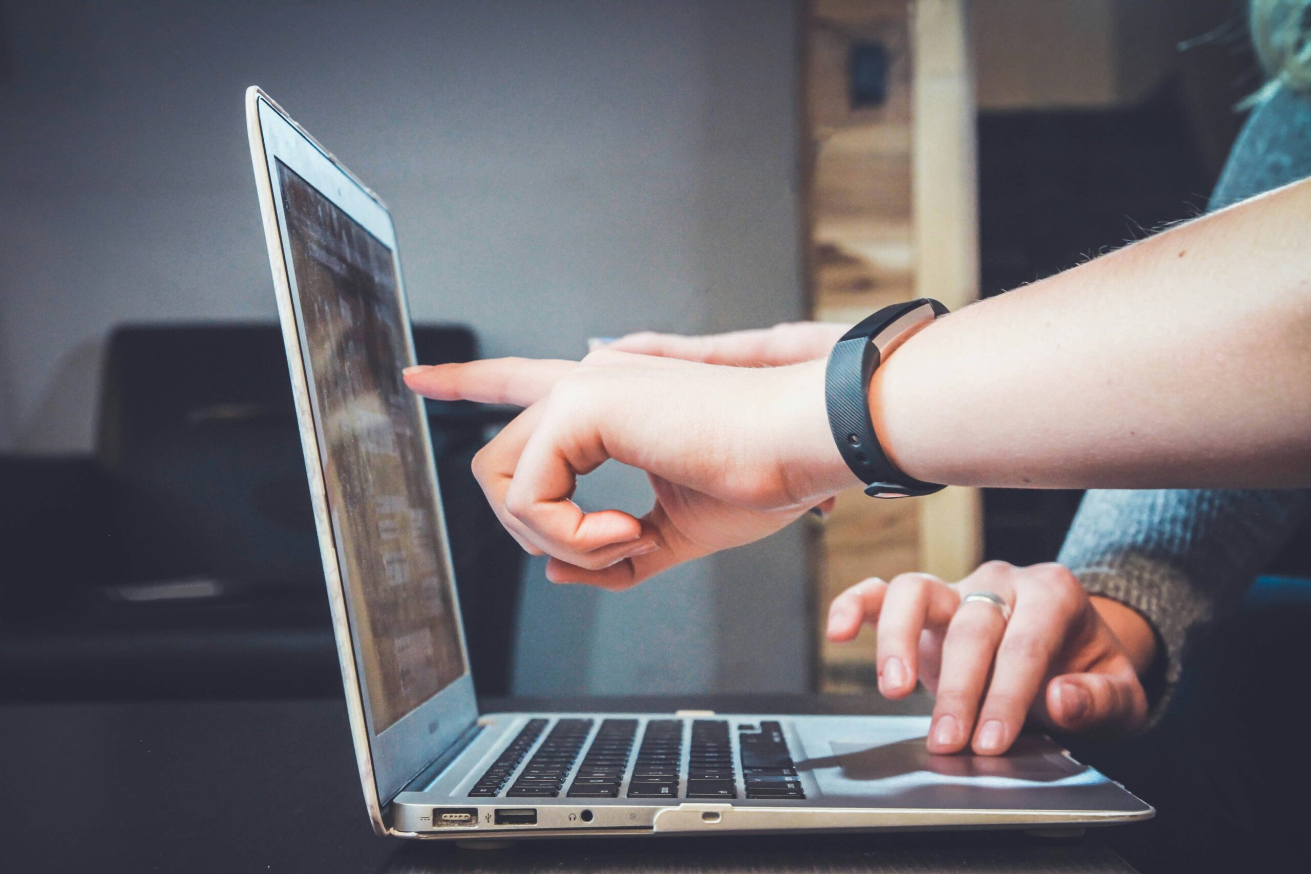 Person applying online on a laptop, pointing at the screen.